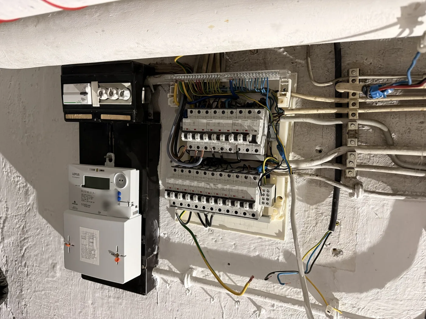 Alte Zähleranlage mit offen verdrahtetem Zählerbrett und Altverteilung vor dem Umbau